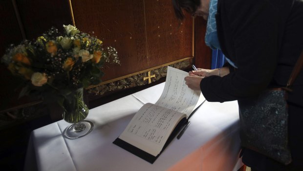 Members of the public sign a book of condolence at Gonville and Caius College.
