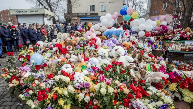 People stand at a floral tribute for the victims of the fire in the Siberian city of Kemerovo.