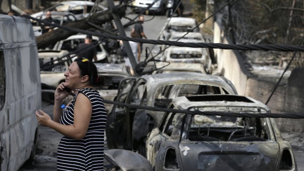 A woman stands amid the charred remains of burned-out cars in Mati.