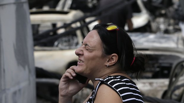 A woman stands amid the charred remains of burned-out cars in Mati.