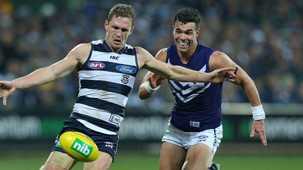 Joel Selwood, sporting a cut eye, gets a rare kick against Ryan Crowley during the Cats' win over the Dockers.