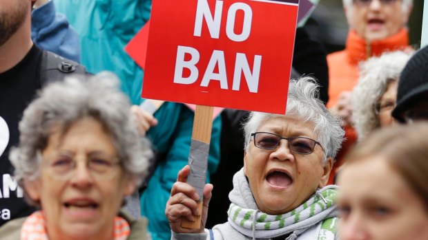 Protesters wave signs and chant during a demonstration in May against Trump's ban.