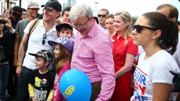 Prime Minister Kevin Rudd removes a LNP balloon from a family photo when he visited the EKKA Brisbane Show on Wednesday.
