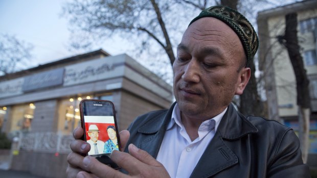 Omir Bekali holds up a mobile phone showing a photo of his parents. He believes they have been detained in China.