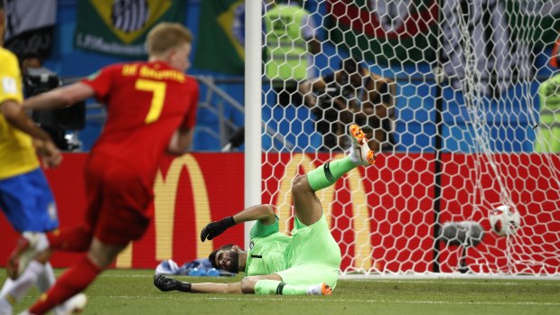 Brazil goalkeeper Alisson sits on the pitch after Belgium's Kevin De Bruyne scores his side's second goal.