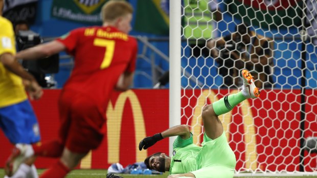 Brazil goalkeeper Alisson sits on the pitch after Belgium's Kevin De Bruyne scores his side's second goal.