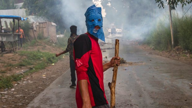 A masked villager holds a wooden stick and stones during a protest south of Srinagar, Indian-controlled Kashmir.