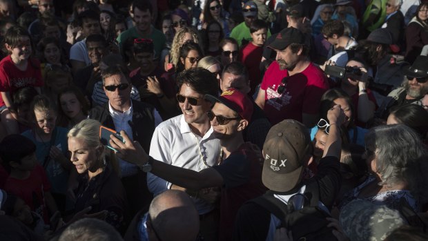 Canadian Prime Minister Justin Trudeau, centre in white, poses for a selfie with a man at a Canada Day barbecue event in Dawson City, Yukon.