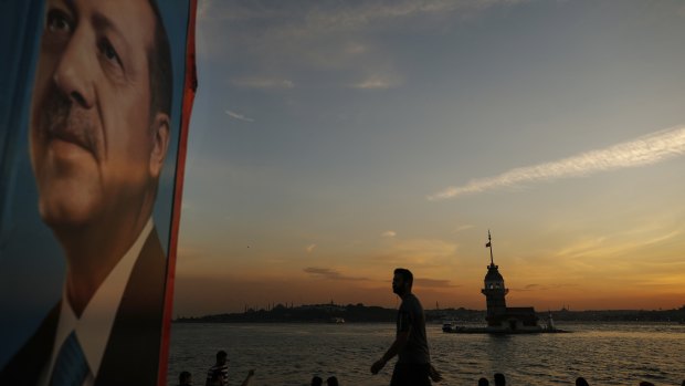 Backdropped by the Bosporus Strait separating Asia and Europe, a man strolls past an election poster of President Recep Tayyip Erdogan, in Istanbul.