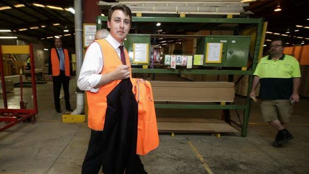 Opposition Leader Tony Abbott's jacket is carried by a staffer during his tour of a door manufacturer in Western Sydney