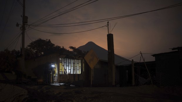 A journalist stands in the doorway of a home, evacuated by its inhabitants near the "Volcano of Fire," in Escuintla, Guatemala, 