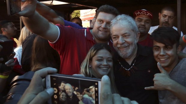 Brazil's former president Luis Inacio Lula da Silva , centre, takes photos with supporters in Quedas do Iguacu, Parana, last month.