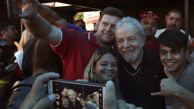 Brazil's former president Lula , centre, takes photos with supporters in Quedas do Iguacu, Parana on Tuesday.