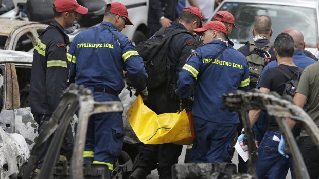 Firefighters remove a dead body in Mati, east of Athens.