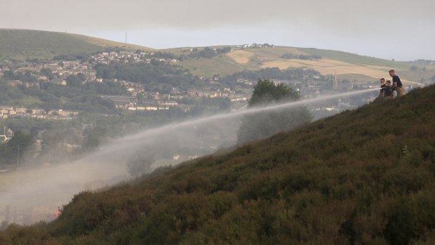 Firefighters work to damp-down land on Saddleworth Moor as a wildfire threatens a nearby village.