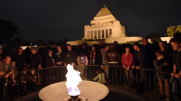 People gather at the Eternal Flame at the Shrine of Remembrance for the ANZAC Day dawn service. 