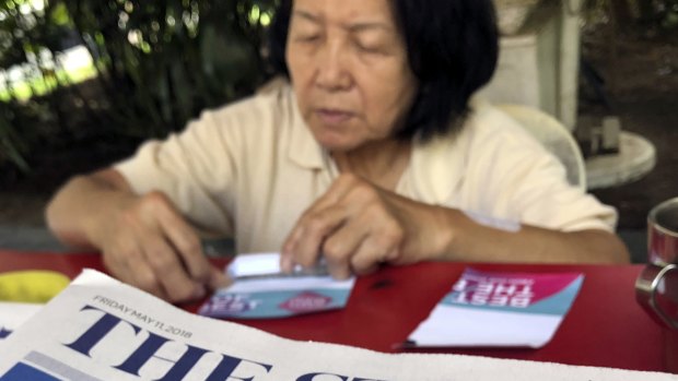A news vendor counts her money near a stack of newspapers with a photo of Trump, right, and Kim on its front page in Singapore. 