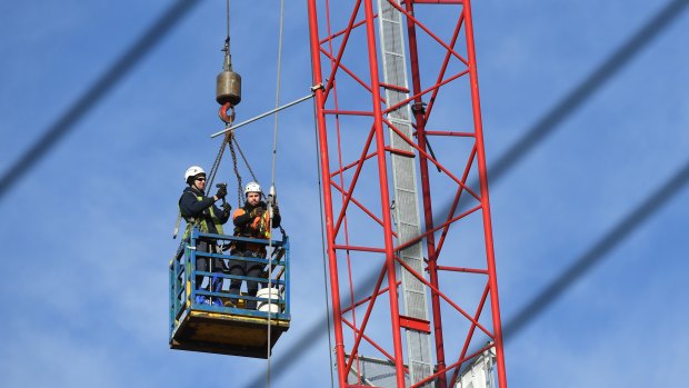 Construction workers are seen dismantling the damaged crane.