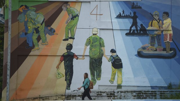 A woman walks pass a mural titled "Migration is not a game of hop scotch," in San Salvador, El Salvador. For now the outrage caused by the policy of separating children from their parents is likely to deter more Central Americans from leaving home, said Andrew Selee, president of the Migration Policy Institute.