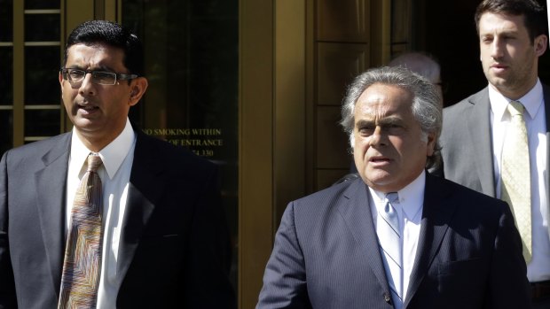 Conservative pundit Dinesh D'Souza, left, accompanied by his lawyer Benjamin Brafman leaves federal court, in New York in 2014.