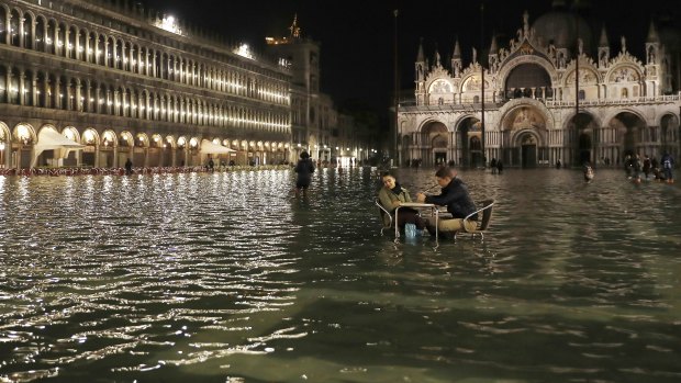 Rising seas: People sit in a flooded St. Mark's Square in Venice, Italy, as high tides inundated the city in March 2018.