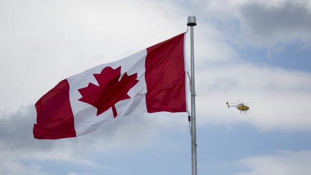 A helicopter flys past a Canadian flag in Niagara Falls, Ontario, Canada.