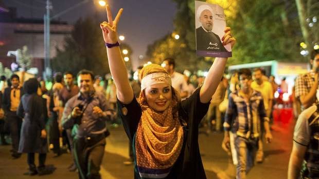A supporter of moderate cleric Hassan Rohani celebrates his victory in Iran's presidential election on a street in Tehran.