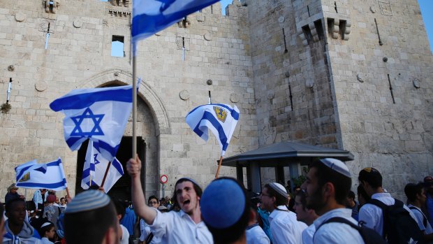  Israelis wave national flags outside the Old City's Damascus Gate, in Jerusalem.
