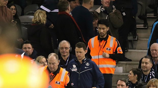 Protected species: Carlton coach Brendon Bolton is flanked by security guards as he makes his way onto the ground during the round 18 clash against Hawthorn