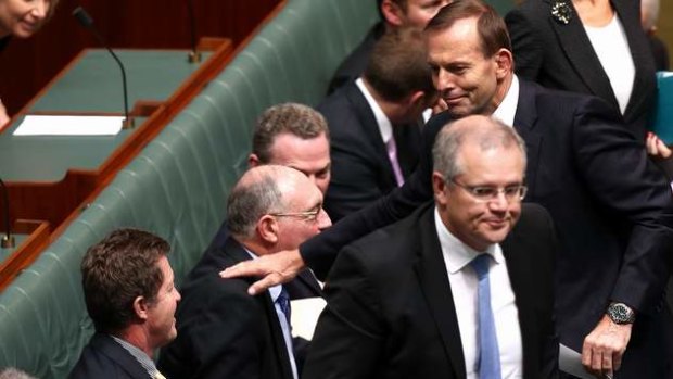 Prime Minister Tony Abbott gives Deputy Prime Minister Warren Truss a pat on the shoulder after a division in the House of Representatives. Photo: Alex Ellinghausen