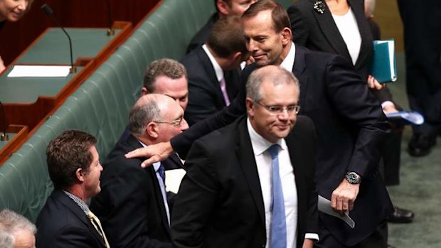 Prime Minister Tony Abbott gives Deputy Prime Minister Warren Truss a pat on the shoulder after a division in the House of Representatives. Photo: Alex Ellinghausen