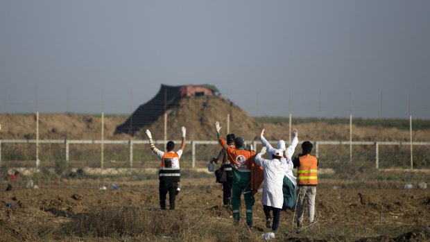 Palestinian medics raise their hands up while walking towards the Israeli side of the border with Gaza to evacuate a injured protester on Monday.