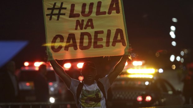 A demonstrator against holds a poster that says in Portuguese "Lula in jail" outside the National Congress in Brasilia.