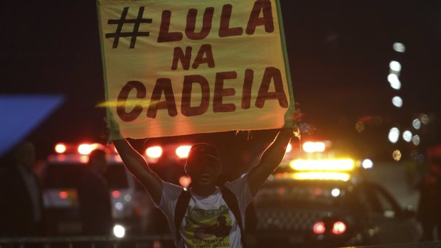 A demonstrator against holds a poster that says in Portuguese "Lula in jail" outside the National Congress in Brasilia.