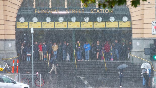 People take shelter at Flinders Street Station as the rain pelted down.