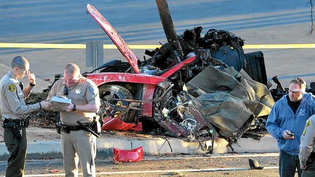 Sheriff deputies work near the wreckage of a Porsche sports car that crashed into a light pole.