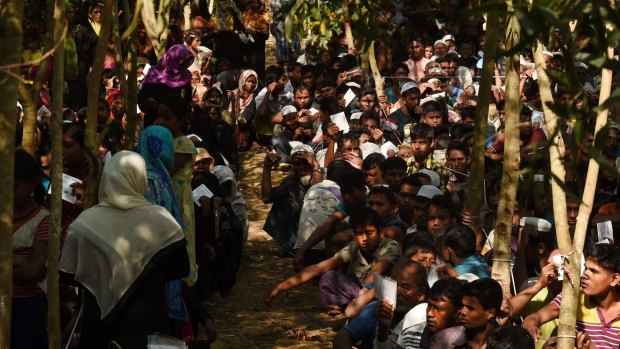 Rohingya refugees sit in a queue at a Red Cross distribution point in Burma Para refugee camp.