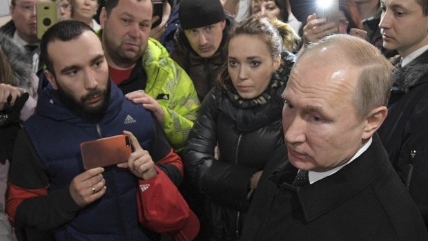 Russian President Vladimir Putin, foreground, listens to locals and relatives in Siberia.