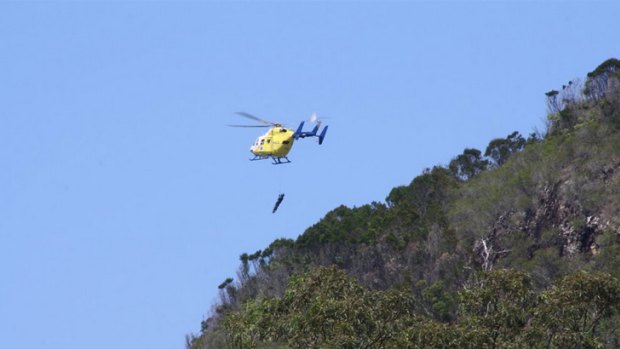 A RACQ CareFlight crewman is lowered onto a bush walking track on Mt Coolum to reach the woman.