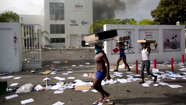 People carry items from a market during protests over a fuel price increase in Port-au-Prince, Haiti.