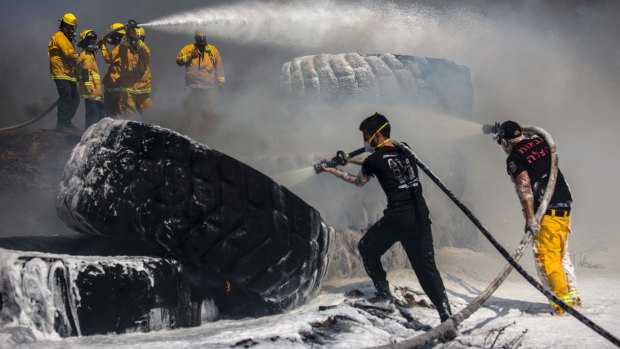 Israeli firefighters extinguish tractor tires in a farmland set on fire by a kite with attached burning cloth launched from Gaza on the Israeli side of the border, Tuesday, May 15, 2018. Israel faced a growing backlash Tuesday and new charges of using excessive force, a day after Israeli troops firing from across a border fence killed dozens of Palestinians and wounded more than 2,700 at a mass protest in Gaza. (AP Photo/Tsafrir Abayov)