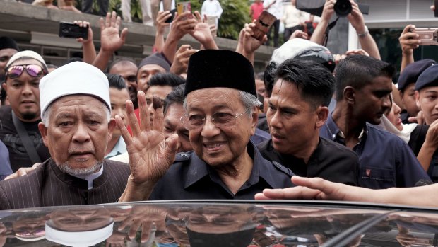 Malaysian Prime Minister Mahathir Mohamad, centre, waves to crowds leaving National Mosque after performing Friday prayers in Kuala Lumpur.