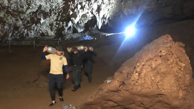 Rescue workers take oxygen tanks into the cave complex.