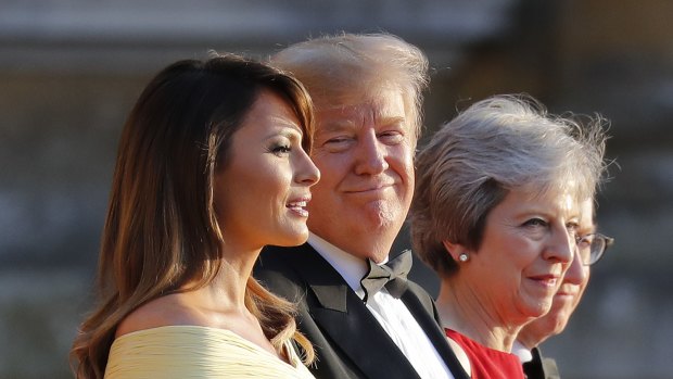 President Donald Trump, second from the right, smiles as he listens to first lady Melania Trump, far left, speak as they stand with British Prime Minister Theresa May at Blenheim Palace.