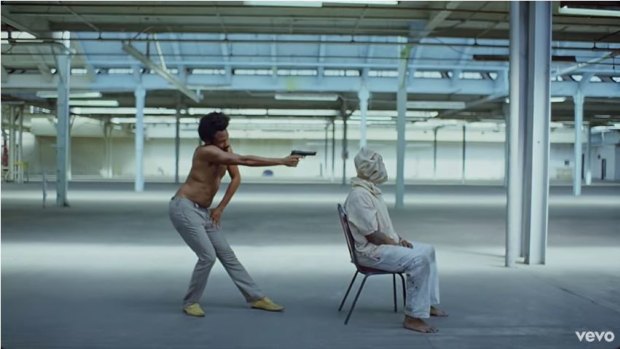 Childish Gambino stands behind Calvin the Second with a gun.