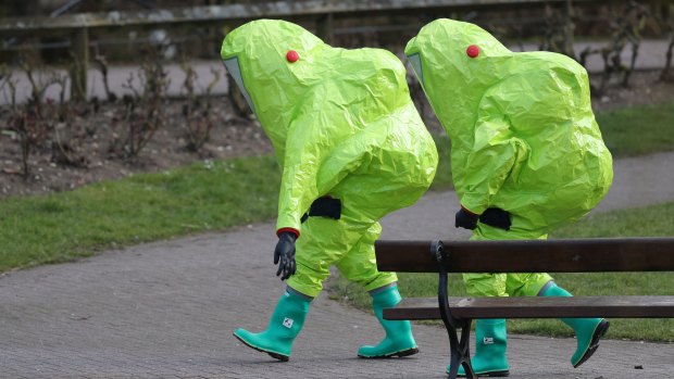 Personnel in hazmat suits walk away after securing the covering on a bench in the Maltings shopping centre where former Russian double agent Sergei Skripal and his daughter Yulia were found critically ill.