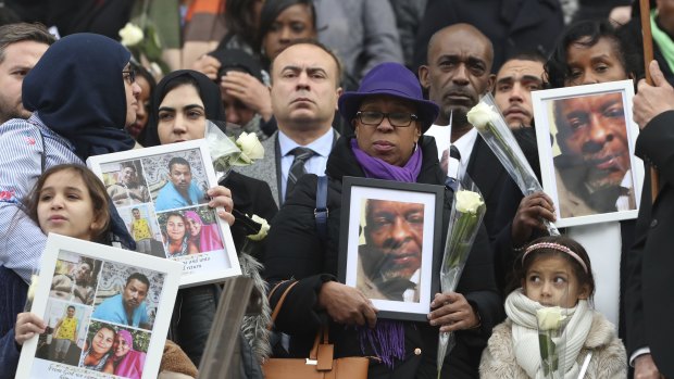 People hold up photos of their loved ones, victims of the fire, as they leave the Grenfell Tower National Memorial Service in London in December.