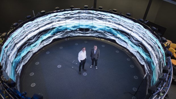 Dr Eric Thrane (left) and Dr Rory Smith at Monash University surrounded by an artist's impression of the background hum of gravitational waves permeating the Universe.