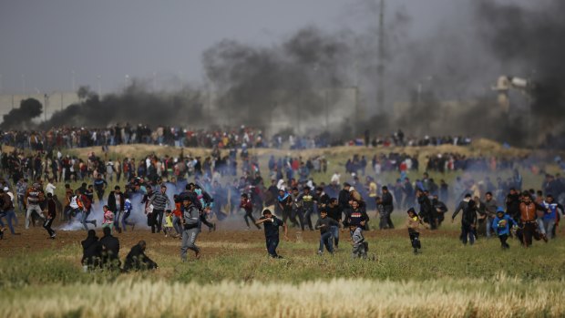 Palestinian protesters run from tear gas after Israeli troops fired canisters at the crowd.