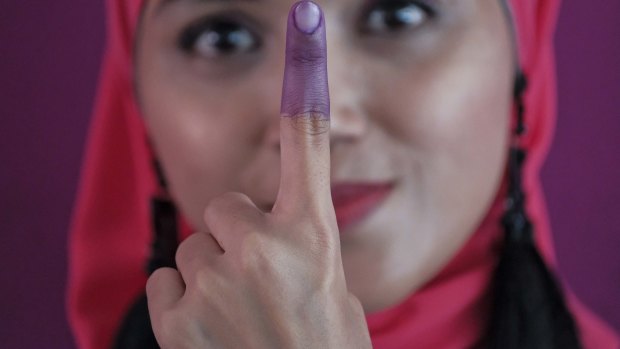 A Malaysian woman shows her inked finger after casting her ballot during the voting day of general elections on Wednesday.